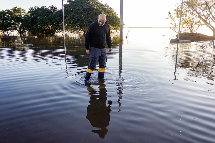 an older man walks in flood waters