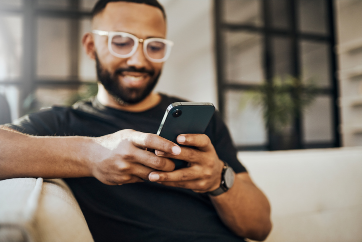 a man smiling while using a smartphone